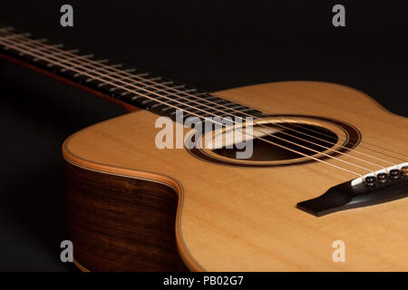 High quality steel-string acoustic guitar. Hand-made wooden musical instrument with European spruce wood top and Ovangkol side. Close-up of body and s Stock Photo