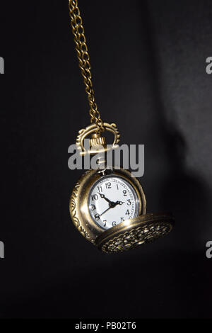 Swinging Opened Vintage Pocket Watch on Black Background - Isolated Metal Clock Stock Photo