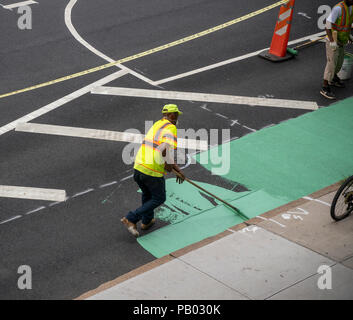 Workers for the New York Department of Transportation (DOT) paint the bicycle lane, after a recent repaving, on Ninth Avenue in the New York neighborhood of Chelsea on Monday, July 16, 2018.  (© Richard B. Levine) Stock Photo