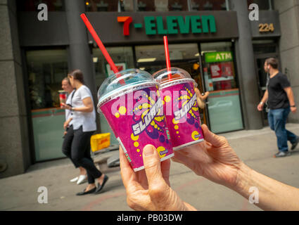 A Slurpee lover displays her Slurpees outside a 7-Eleven store in New York on Wednesday, July 11, 2018 (7-11, get it?), Free Slurpee Day! The popular icy, slushy, syrupy drinks are available in regular and diet flavors, in combinations, and the stores have stocked up with extra barrels of syrup to meet the expected demand. According to the meticulous figures kept by 7-Eleven they sell an average of 14 million Slurpees a month and over 150 million Slurpees a year.  (© Richard B. Levine) Stock Photo