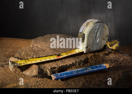 Old used measure tapes on the stone and dark background with pencil Stock Photo