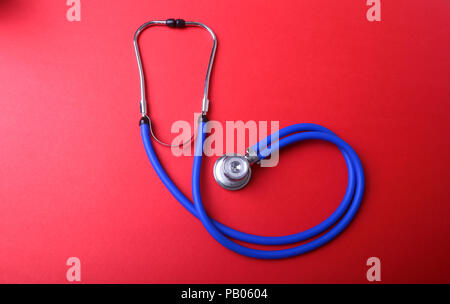 Medical blue stethoscope isolated on red background. Stock Photo