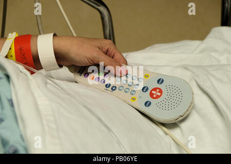 Woman patient changing television channels with remote control device in hospital after surgery. Stock Photo