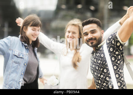 Three friends in the city with their arms in the air Stock Photo