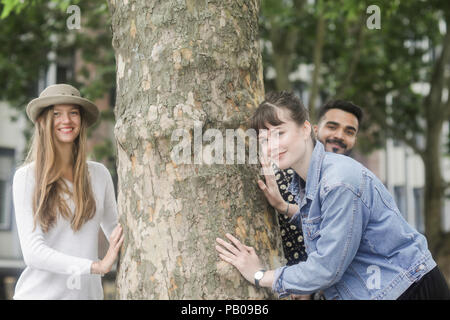Three friends messing about by a tree in the city Stock Photo