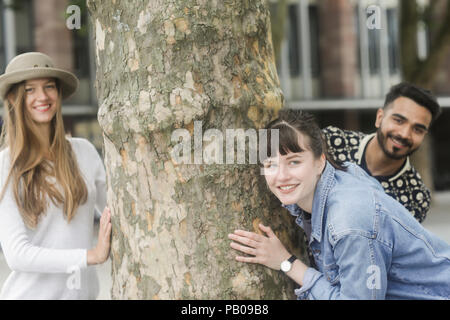 Three friends messing about by a tree in the city Stock Photo