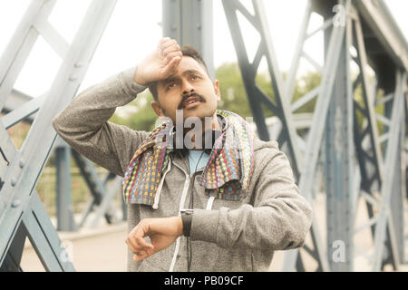 Jogger standing on a footbridge with his hand on his head Stock Photo