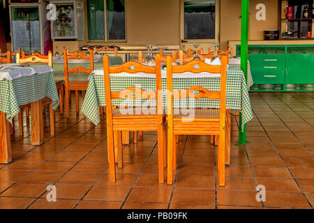 Spanish outdoor restaurant with wooden tables and chairs on red tiles Stock Photo