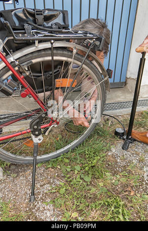 Woman pumps up bicycle tire Stock Photo