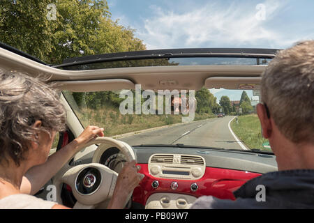 Grey haired man and woman inside an open sportscar in summer Stock Photo