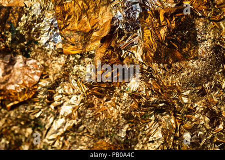 Shiny yellow gold leaf or scraps of gold foil background texture, surface from Back of Buddha image. Stock Photo