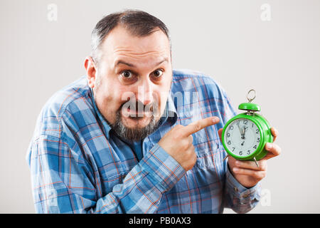 Portrait of man holding a clock that shows five to twelve time Stock Photo