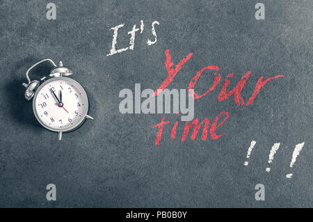 Alarm clock lies on a countertop with a motivational inscription 'It's Your time' Stock Photo