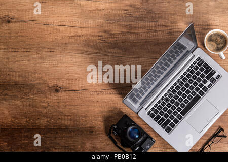 Modern laptop, coffee and an old analogue camera lie in the corner of the desk. Photo contains copyspace Stock Photo