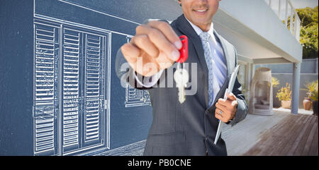 Composite image of confident estate agent standing at front door showing key Stock Photo