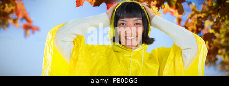 Composite image of woman wearing yellow raincoat against white background Stock Photo