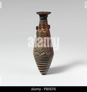 Glass alabastron (perfume bottle). Culture: Greek, Eastern Mediterranean. Dimensions: H.: 4 11/16 in. (11.9 cm). Date: 2nd-mid-1st century B.C..  Translucent deep turquoise blue, with handles in same color; trail in opaque white.  Moderately broad rim-disk, sloping inward, with projecting jagged inner edge to neck; slender cylindrical neck, expanding downwards; straight-sided fusiform body expanding downward, then tapering in to pointed bottom; two lug handles applied over trail at top of body.  Trail attached near bottom, drawn up in a spiral to point of carination, tooled into a close-set fe Stock Photo