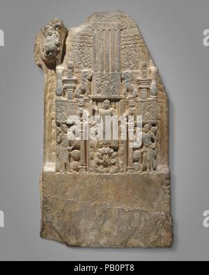 Drum Slab Showing the Buddha Standing in the Gateway of a Stupa. Culture: India (Andhra Pradesh, Nagarjunakonda). Dimensions: H. 48 in. (121.9 cm); W. 29 3/4 in. (75.6 cm); D. 6 3/4 in. (17.1 cm); Est. Wt. 723.3 lbs (328.1 kg). Date: second half of the 3rd century.  This limestone panel was part of a series that encircled the drum of a large stupa. It shows the Buddha standing in the gateway of a stupa being venerated by two female devotees. Attendants holding fly whisks (chauris) stand at either side of the gateway, which is crowned by lions. This detailed imagery documents what a stupa and i Stock Photo