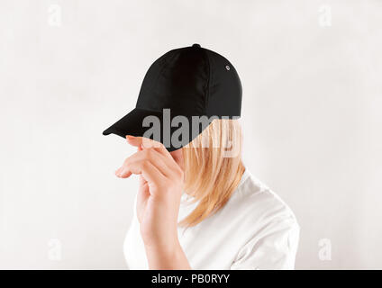 Blank black baseball cap mockup template, wear on women head, isolated, side view. Woman in clear grey hat and t shirt uniform mock up holding visor o Stock Photo