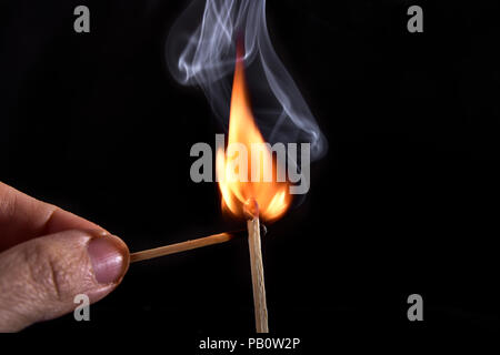 Close up of a match on a black background. I lit a matchstick on a dark background to see all the details of the sequence of ignition. Stock Photo
