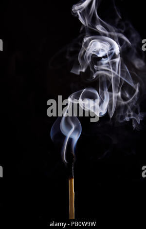 Close up of a match on a black background. I lit a matchstick on a dark background to see all the details of the sequence of ignition. Stock Photo