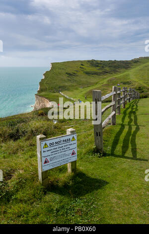 Hope Gap on the Vanguard Way public footpath in front of a sign warning of falling rock and cliff erosion near Seaford, East Sussex, England. Stock Photo