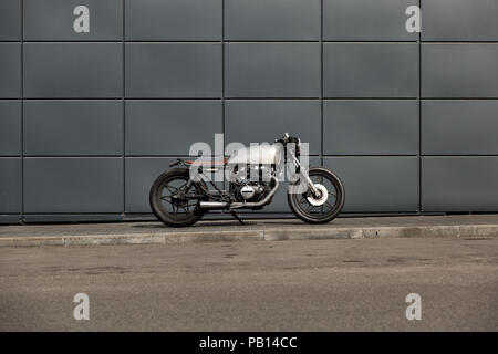 Handmade motorbike parking near gray wall of finance building. Everything is ready for having fun driving the empty road on a motorcycle tour journey. Stock Photo