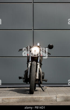 Vintage motorbike parking near gray wall of finance building. Everything is ready for having fun driving the empty road on a motorcycle tour journey.  Stock Photo