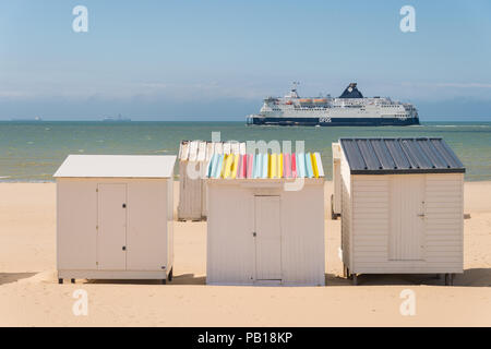 Calais, France - 19 June 2018: Beach cabins and DFDS cross Channel ferry on its way to Dover, UK. Stock Photo