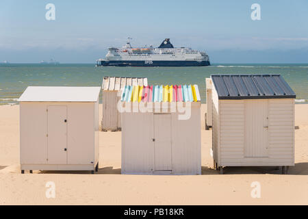 Calais, France - 19 June 2018: Beach cabins and DFDS cross Channel ferry on its way to Dover, UK. Stock Photo