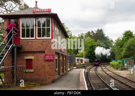 Steam train engine approaching Lakeside and Haverthwaite railway station signal box in Lake District National Park. Lakeside, Cumbria, England, UK Stock Photo