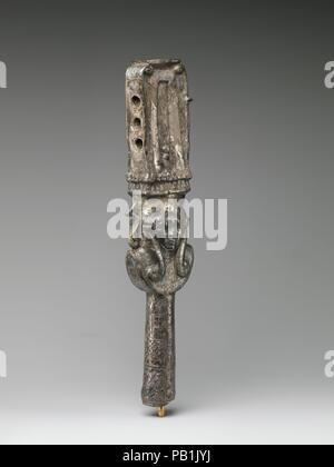 Sistrum with a dedication referring to a king. Dimensions: H. 29.6 × W. 6.9 × D. 4.2 cm (11 5/8 × 2 11/16 × 1 5/8 in.). Dynasty: Ptolemaic Dynasty. Date: 332-30 B.C..  The sistrum was a a sort of rattle, its rustling sound associated in particular with great female goddesses, for instance Tefnut, Hathor, Isis, or Bastet.  Like all Egyptian sistra, this one has the emblem of Hathor/Bat, the frontal head of a female with cow ears, at the juncture of the upper part and the handle. Above the goddess's head, a naos or shrine forms the sound-box. The naos in this instance is not openwork, so that di Stock Photo