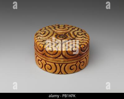 Box with pommel-scroll design. Culture: China. Dimensions: H. 1 7/8 in. (4.8 cm); Diam. 3 1/2 in. (8.9 cm). Date: late 13th-14th century.  The decoration covering the surface of this box is sometimes known as a pommel-scroll design because it resembles the shape of sword's pommel. A flowering plum tree and crescent moon made of ivory, gold leaf, lacquer, and glass, are inlaid into the interior of the cover. The motif may allude to any number of earlier poems that evoke the shadows of plum blossoms by moonlight in a night filled with their scent. Museum: Metropolitan Museum of Art, New York, US Stock Photo