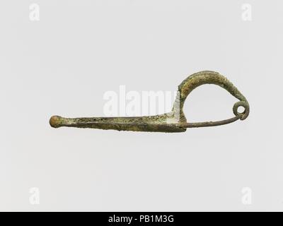 Bronze sanguisuga-type fibula (safety pin). Culture: Etruscan. Dimensions: Other: 4 1/16 in. (10.3 cm). Date: 7th century B.C..  The bow is solid and decorated on its upper surface with a series of ridges. The head is formed by a spiral of two turns. Museum: Metropolitan Museum of Art, New York, USA. Stock Photo