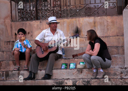 Man playing his guitar on the steps of a church in Trinidad, Cuba Stock Photo
