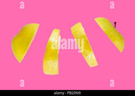 Green ripe apple cut slices in the air isolated on pink background. Levity fruit floating in the air concept Stock Photo