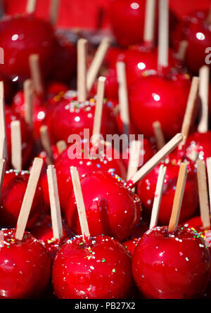 Sweet glazed red toffee candy apples on sticks for sale on farmer market or country fair Stock Photo