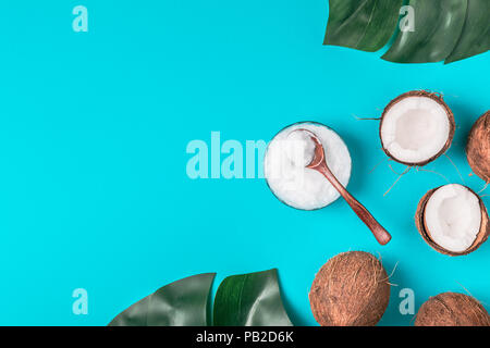 Coconut oil and coconuts on a background with tropical leaves. Stock Photo