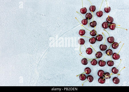 Sweet red cherries on beautiful blue cement background with lots of copy space. Stock Photo