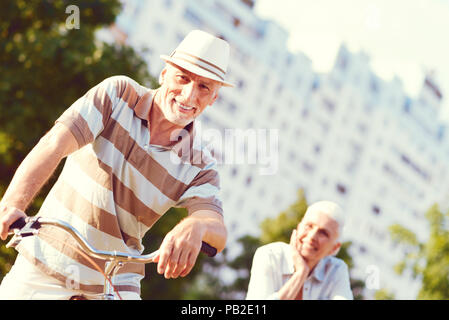 Beaming senior man leaning on bicycle outdoors Stock Photo