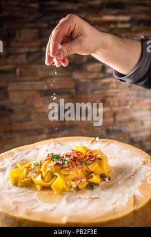 Chef in restaurant exclusively preparing italian pasta pappardelle on a block cheese parmesan. Stock Photo