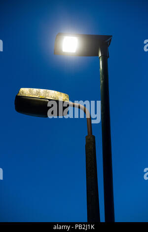 Street lamp head / light / lights / lamps of an older sodium technology (left) which are in the process of being replaced by LEDs / LED (right). (100 Stock Photo