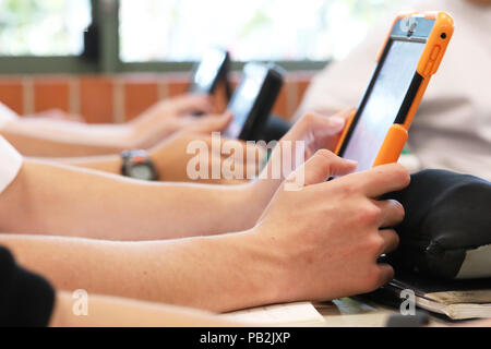 High school students working on using an ipad tablet style electronic computer device. modern pedagogy and teaching learning in education educational Stock Photo