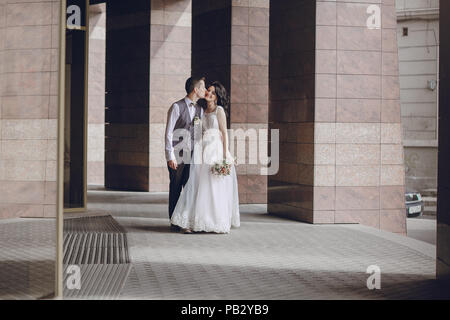 bride and groom stand near tall columns Stock Photo