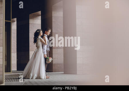 bride and groom stand near tall columns Stock Photo