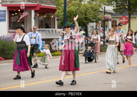 Frankenmuth, Michigan, USA - June 10, 2018 Men and women wearing traditional german clothing going down the road waving american flags at the Bavarian Stock Photo