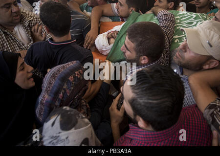 Gaza, Gaza Strip, Palestine. 26th July, 2018. Mourners carry the body of Palestinian Hamas militant Mohammad Al-Areer who was killed in Israeli tank fire, during his funeral in Gaza City.The military wing of Gaza's rulers Hamas have vowed revenge after Israeli strikes late July 25 killed three members of the group in the latest flare-up of violence. Israel said the artillery fire late Wednesday was in retaliation for shots fired at troops along the border which injured one soldier. Credit: Mahmoud Issa/SOPA Images/ZUMA Wire/Alamy Live News Stock Photo