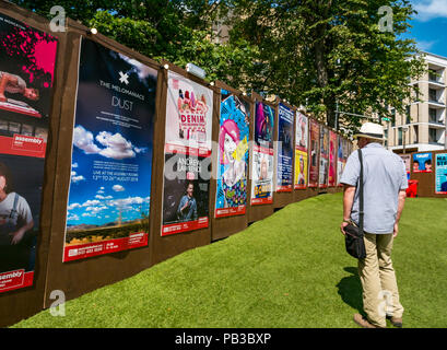 Edinburgh Food Festival 2018 in George Square Gardens, Edinburgh, Scotland, United Kingdom. There are food stalls with over 20 local food and drink producers in the free outdoor event. A man wearing a Panama hat looks at Edinburgh Fringe Festival posters in George Square which include Andrew Lawrence, Out of the Blue singers, Simon Evans and The Melomaniacs Stock Photo