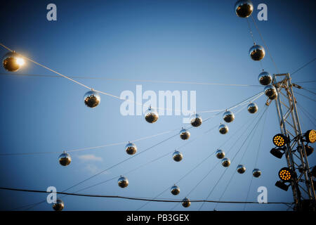 Several mirror disco balls strung up with professional lighting equipment for an outdoor event Stock Photo