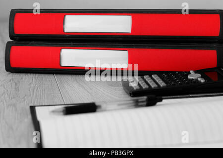 Red folders with blank labels on the spine on a desk with selective colour Stock Photo